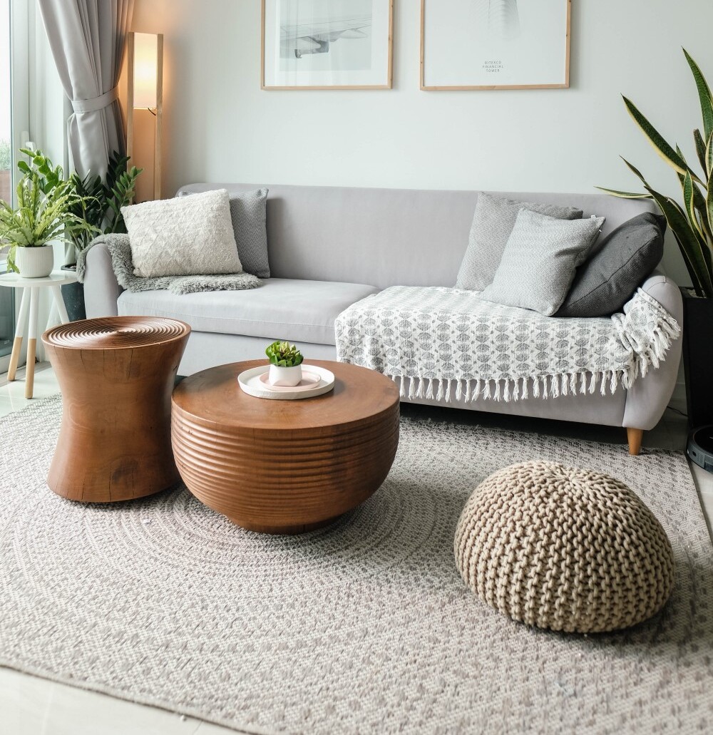 a large rug taking up the majority of the floor in a living room, featuring a sofa, coffee table, a side table, and other decorations