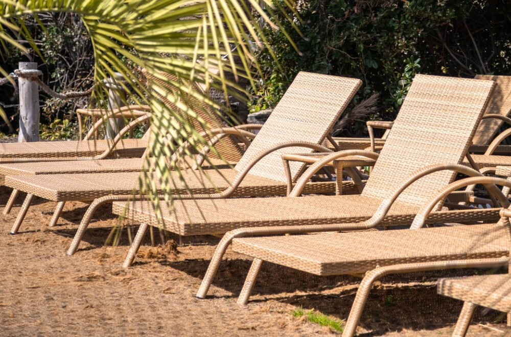 A row of rattan  sunbeds placed on a garden patio